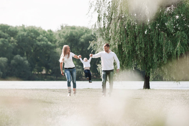 happy parents with their little son walking together in spring Park - 写真・画像