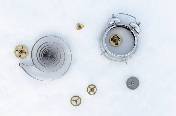 Broken clock with scattered gears on white snow. - Zdjęcie, obraz