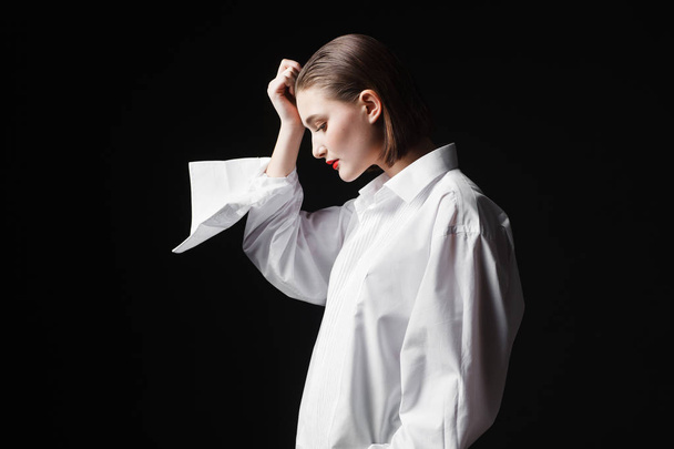 Portrait of an elegant young woman in a white shirt and black pants. Interesting studio light - Фото, изображение