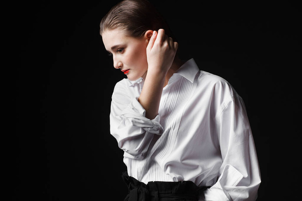 Portrait of an elegant young woman in a white shirt and black pants. Interesting studio light - Fotó, kép