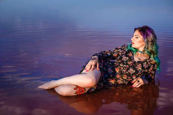 ピンクの水で湖のほとりに砂の上のセクシーな女性 - 写真・画像