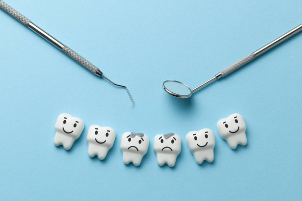 Fehér fogak fogszuvasodás, a kék háttér és a fogorvos eszközöket tükör, kampó. - Fotó, kép