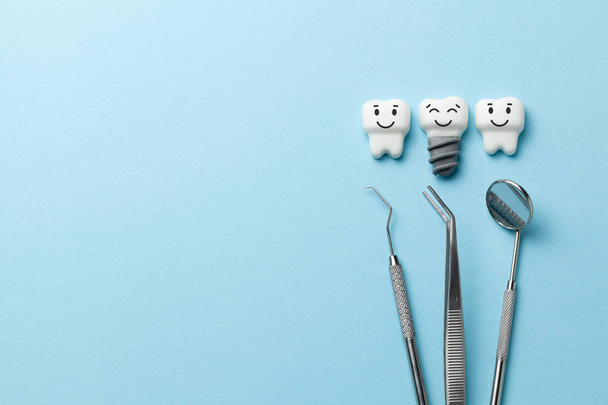 Dents blanches saines et implants sourient sur fond bleu et outils dentiste miroir, crochet. Espace de copie pour le texte
. - Photo, image