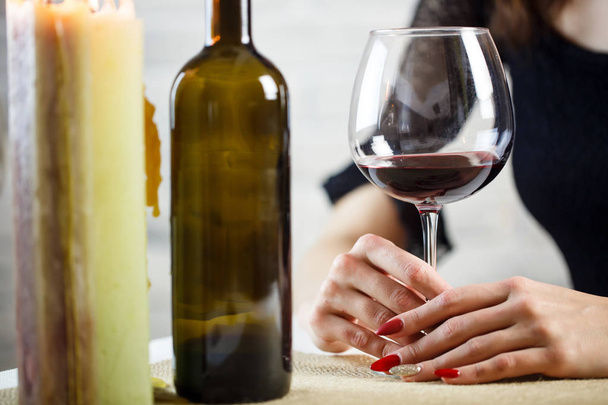 Uma mulher segura na mão um copo de vinho num encontro às cegas. Dois copos de vinho na mesa. Fechar
. - Foto, Imagem