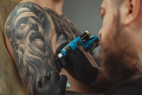 Профессиональный татуировщик делает новую татуировку для своего клиента
 - Фото, изображение