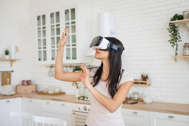 Young woman in VR glasses in kitchen at home - Foto, Imagem