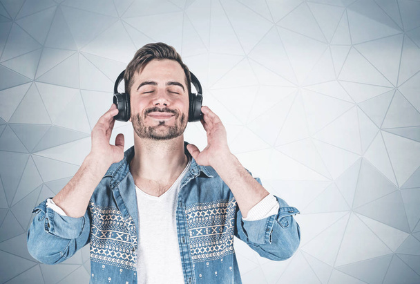 Smiling man listening to music, wall - Фото, изображение