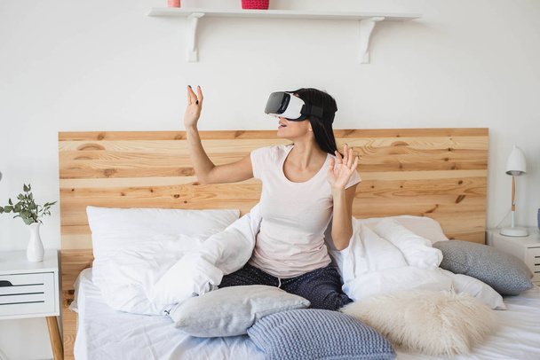 Portrait of smiling happy young woman getting experience using VR glasses at home - Foto, Imagem