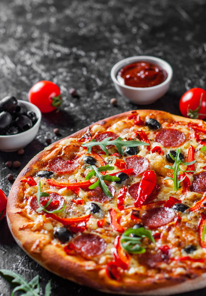 Pepperoni Pizza with Mozzarella cheese, salami, Tomatoes, olive, pepper, Spices and Fresh arugula. Italian pizza on dark background - Foto, Imagen