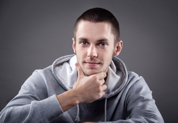 Closeup of young man with hand on head on gray background - Foto, Imagen