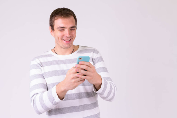 Portrait of happy man smiling while using phone - Foto, Bild