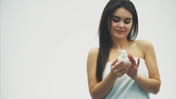 Close-up of a beautiful young girl with creamy lotion, which relates to her shoulder, feeling happy and cheerful for the moisture of her healthy skin, the concept of skin care. - Materiał filmowy, wideo
