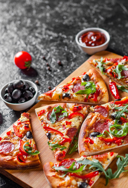 Pepperoni Pizza with Mozzarella cheese, salami, Tomatoes, olive, pepper, Spices and Fresh arugula. Italian pizza on dark background - Fotografie, Obrázek