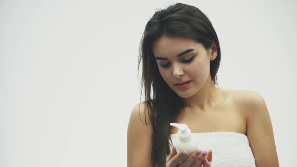 Close-up of a beautiful young girl with creamy lotion, which relates to her shoulder, feeling happy and cheerful for the moisture of her healthy skin, the concept of skin care. - Záběry, video
