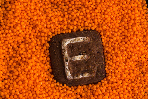 Kekse mit Buchstaben auf dem Hintergrund orangefarbener süßer Kugeln - Foto, Bild