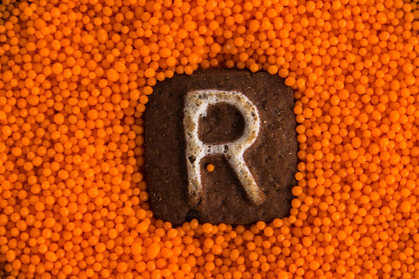 Kekse mit Buchstaben auf dem Hintergrund orangefarbener süßer Kugeln - Foto, Bild