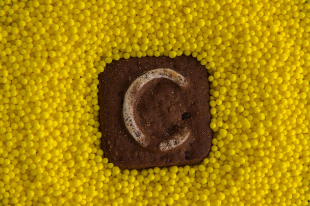 буквы английского алфавита на фоне желтых сладких шариков
 - Фото, изображение