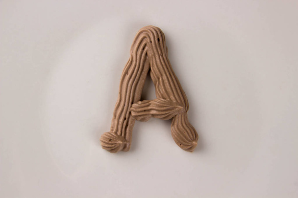 Γλυκό σοκολάτας γράμμα A που σύρεται με κρέμα σαντιγί σε ένα άσπρο πιάτο - Φωτογραφία, εικόνα