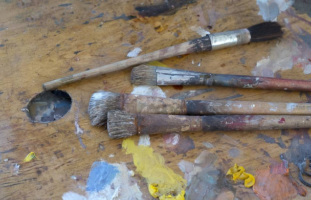Старий пензлі та фарби по брудні палітру в студії художника - Фото, зображення