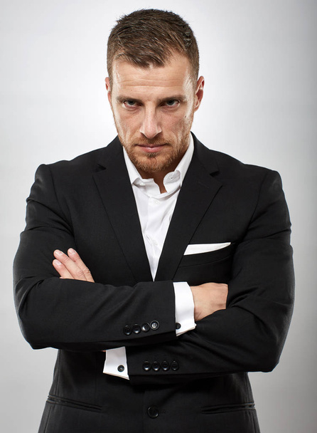 Unhappy businessman frowning with arms folded - Фото, изображение