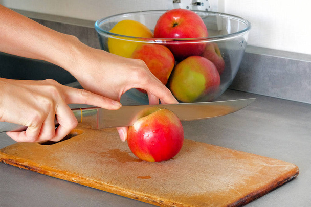 Concepto de cocina. Manzanas está cortando en rodajas en tablero de madera en la mesa de la cocina
. - Foto, imagen