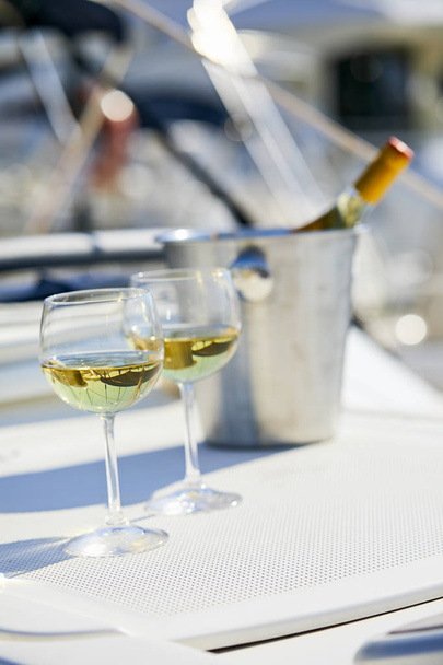 Ζευγάρι wineglasses και κουβά με μπουκάλι κρασί στο γιοτ - Φωτογραφία, εικόνα