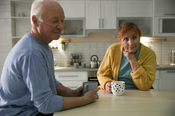 Elderly couple drinking tea at table in kitchen - Foto, imagen