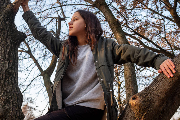 Krásné dospívající dívka stojící mezi větve stromů a hledat dál - Fotografie, Obrázek