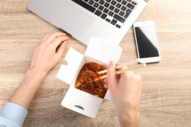 Woman eating Chinese noodles at workplace, closeup with space for text. Food delivery - Фото, зображення