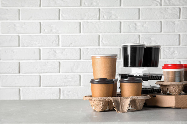 Various takeout containers on table against white brick wall, space for text. Food delivery service - Photo, Image