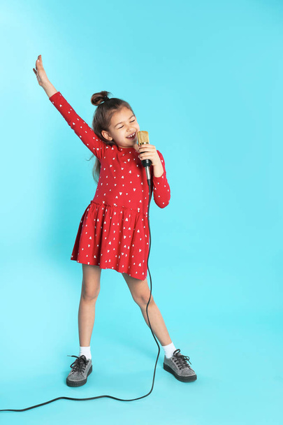 Cute funny girl with microphone on color background - Fotoğraf, Görsel