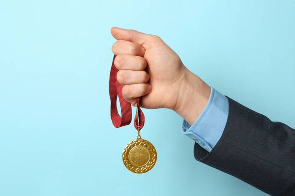 Man holding golden medal on color background, closeup. Space for text - Foto, immagini