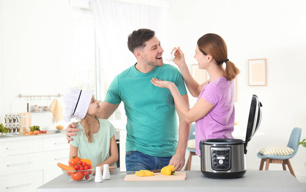 Happy family preparing food with modern multi cooker in kitchen - Fotó, kép