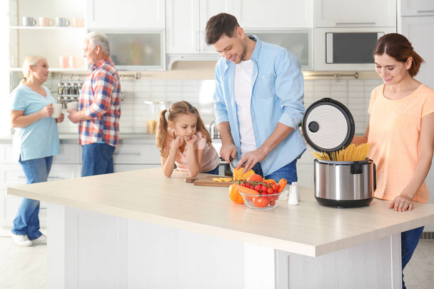 幸せな家族が台所で近代的なマルチ調理器と食品の準備 - 写真・画像