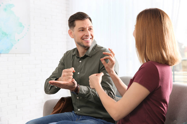 Порушення слуху друзів, використовуючи мову жестів для спілкування на дивані у вітальні
 - Фото, зображення