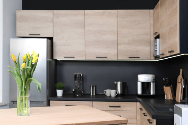 Ваза с тюльпанами на столе в уютном современном кухонном интерьере, избирательный фокус
 - Фото, изображение