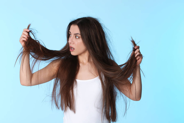 Emotional woman with damaged hair on color background. Split ends - 写真・画像