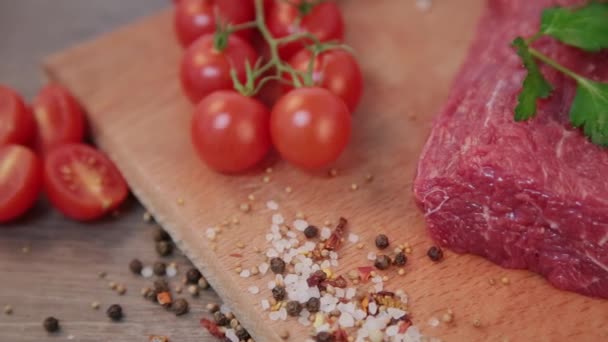 raw beef on a wooden background with spices and tomatoes. - Footage, Video
