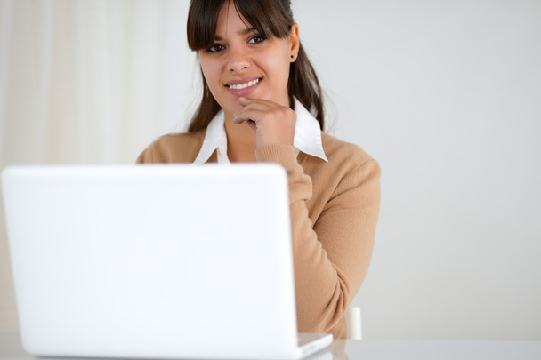 Улыбающаяся женщина смотрит на тебя и использует свой ноутбук
 - Фото, изображение