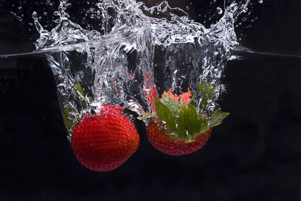 Two strawberries dropped in water. - Photo, Image