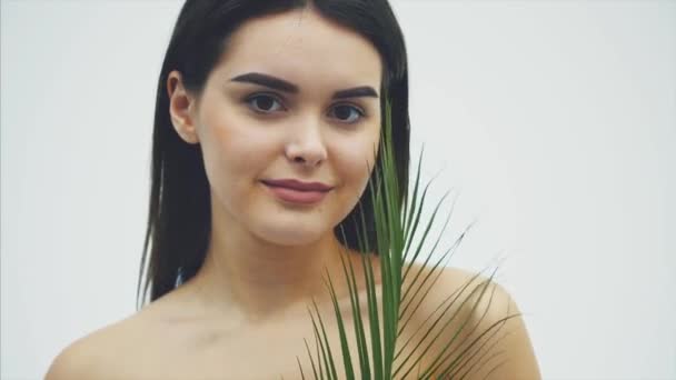 Young beautiful smiling model with natural makeup, long eyelashes and green leaf of ferns. Spa, skin care and wellness. Beauty and Skin Care Concepts. - Filmati, video