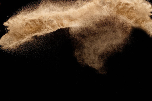 Droge rivier zand met stenen explosie. Geel gekleurde zand splash die donkere achtergrond. - Foto, afbeelding