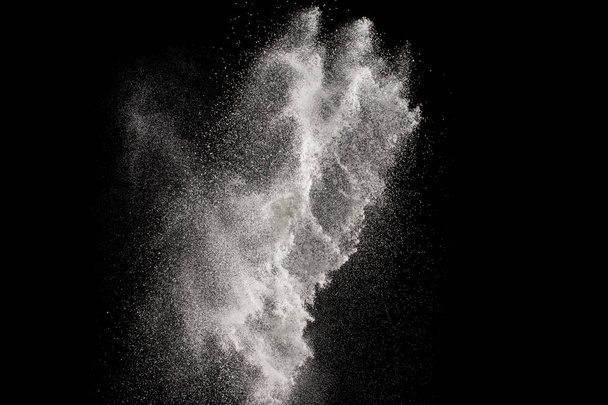 Congelar el movimiento de partículas blancas sobre fondo negro. Explosión abstracta de polvo blanco
. - Foto, Imagen