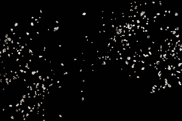 Studio shot of black  stone textured splatter in black background. Split debris of stone caused by explosion against black background. - Photo, Image