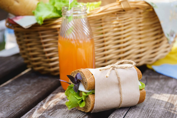 Sandwich with egg, lettuce, basil and a bottle of fresh juice. - Foto, afbeelding