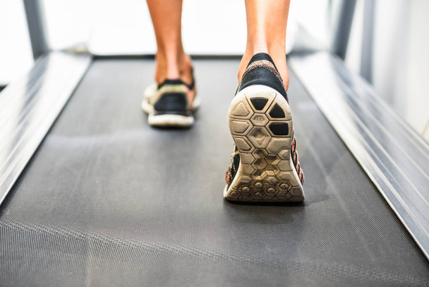 Мужские мускулистые ноги в кроссовках бегают по беговой дорожке в спортзале
. - Фото, изображение