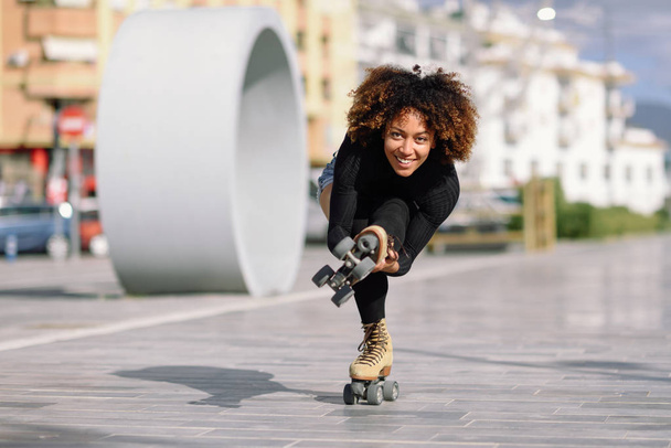Black woman on roller skates riding outdoors on urban street - Fotoğraf, Görsel