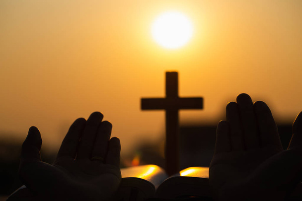 Silhouette of young woman praying with crosses and bibles at sun - Photo, Image