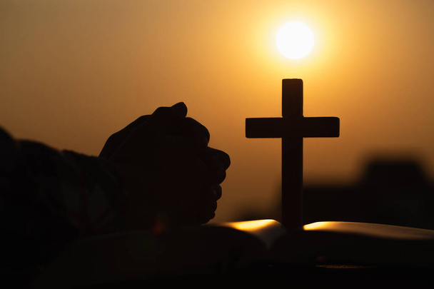 Silhouette of young woman praying with crosses and bibles at sun - Photo, Image