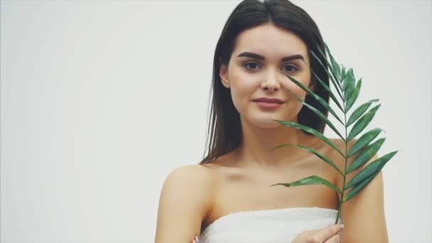 Beautiful young woman with perfect skin and natural make up posing front of plant tropical green leaves background with fern. Young model with wet hair care of her face and body. - Imágenes, Vídeo